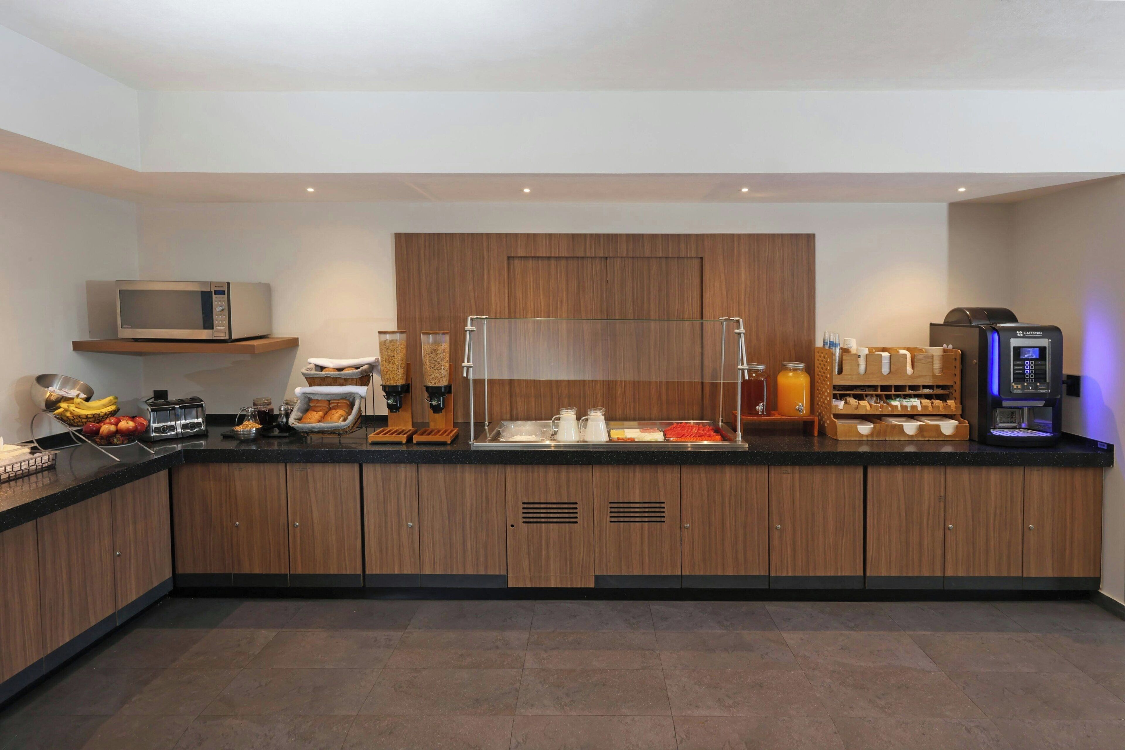 A modern kitchen with a microwave, coffee machine, and various food items on the counter.