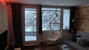 A cozy living room with a wooden interior, a hanging chair, a sofa, and a television. - Fantastic vacation apartment "Waldhonig" (St. Englmar)
