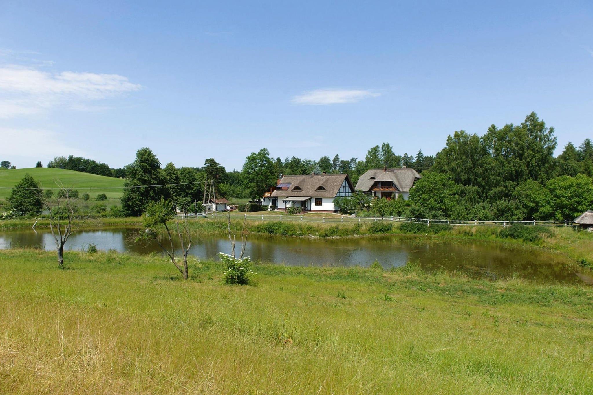 A rural landscape with a pond, houses, and a fence.