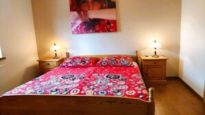 A bedroom with a wooden bed, two bedside tables with lamps, and a wall-mounted painting. - Apartment only 20 m from  Lake in Rekowo (Rekowo)
