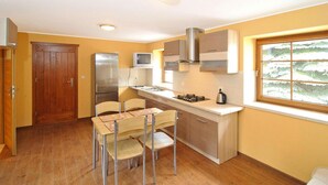 A compact kitchen with a dining area, wooden door, and a window with a view.