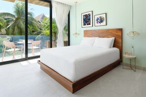 A modern bedroom with a large bed, a balcony with chairs, and tropical views. - CALIXTA Hotel (Playa del Carmen)