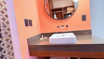 A bathroom with a round mirror, a white sink, and a towel rack.