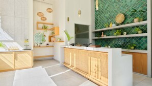 Een moderne keuken met witte kasten, een bamboe aanrechtblad en een groene tegelwand.