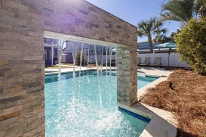 Piscina com parede de pedra e uma cascata.