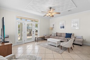 A living room with a ceiling fan, a television, a sofa, a coffee table, and a bench.