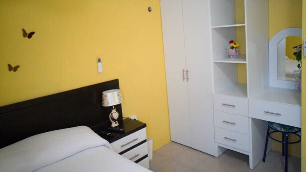 Un dormitorio con cama, mesita de noche, cómoda, espejo y armario.