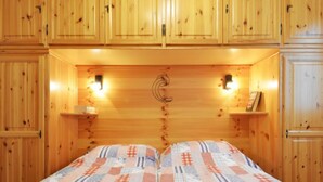 Een houten kamer met twee bedden, houten kasten en wandlampen.