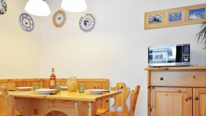 Een houten eettafel met stoelen, een magnetron en een kast in een keuken.