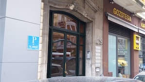 Entrada de edificio con un letrero de estacionamiento 'P', un letrero 'Gozotegia' y un letrero 'KAF'.