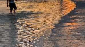 A sunset at the beach with two children walking along the shore. - 30 STEPS - BEACHFRONT LUXURY OASIS! PRIVATE POOL AND HOT TUB!  (Fort Myers Beach)
