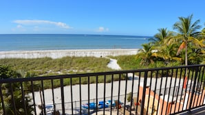 A balcony with a view of the beach, a pool, and a dining area. - 30 STEPS - BEACHFRONT LUXURY OASIS! PRIVATE POOL AND HOT TUB!  (Fort Myers Beach)