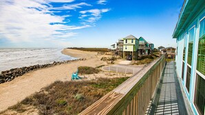 A wooden deck with a view of the beach and ocean.