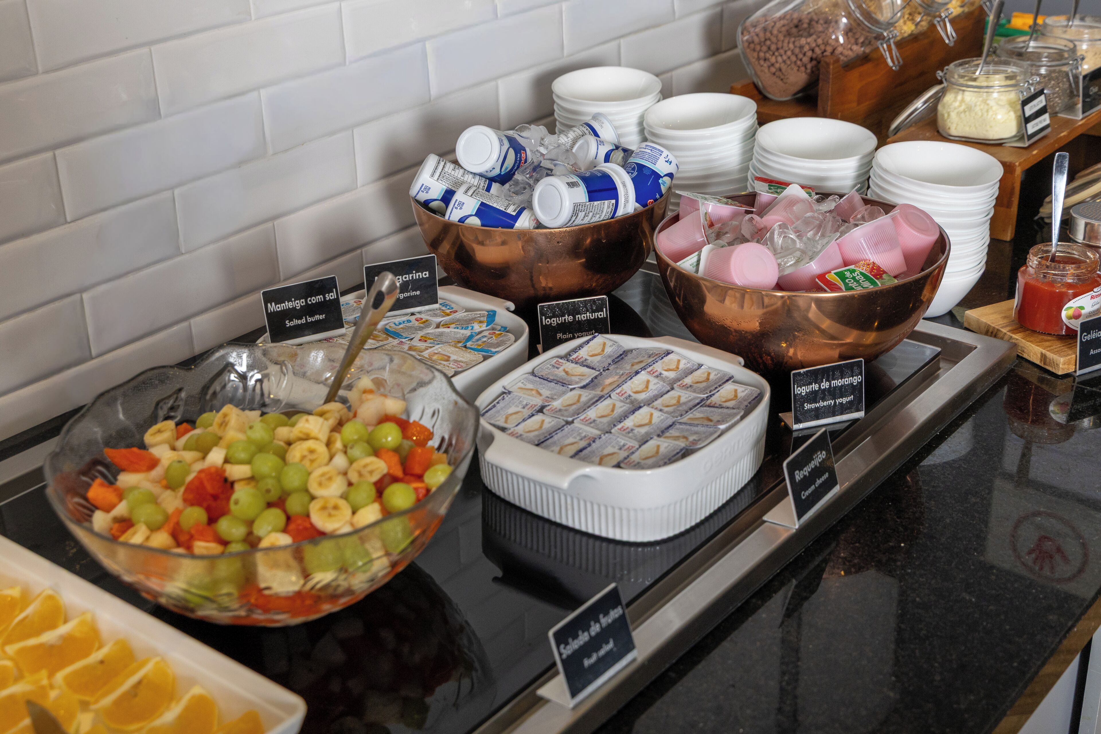 Um buffet com diversas opções de comida, incluindo salada de frutas, iogurte e outros pratos prontos.