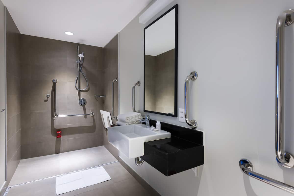 Un baño moderno con ducha, lavamanos y espejo.