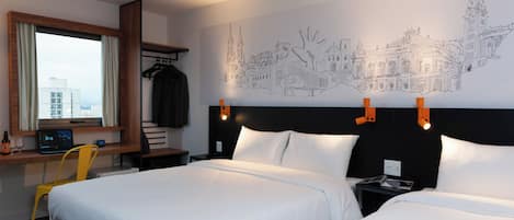 Una habitación de hotel con dos camas, un escritorio con una computadora portátil, una silla, una ventana con cortinas y un mural en la pared.