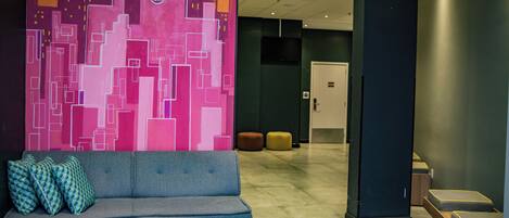 A lobby with a modern sofa, a colorful abstract wall, and a door in the background.