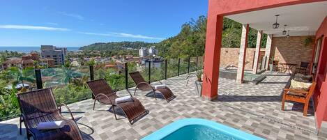 Zona de piscina en la azotea con sillones de descanso, una piscina pequeña y vistas a la ciudad.
