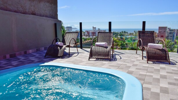 Área de piscina no terraço com espreguiçadeiras e vista para a paisagem urbana.