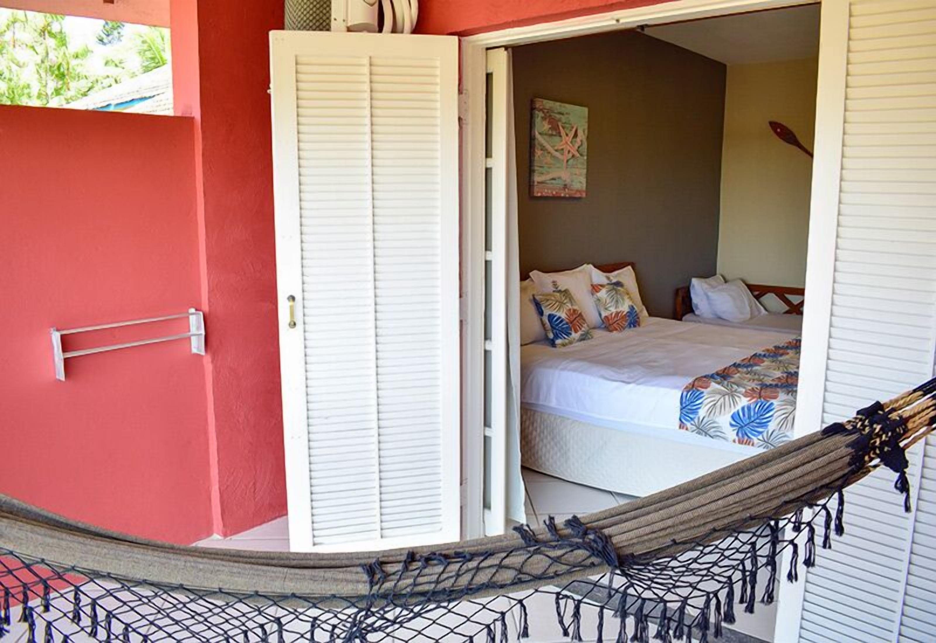 Una habitación con una cama, una hamaca y una puerta que da a otra habitación.