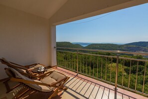Un balcon avec vue sur des collines verdoyantes et un ciel dégagé.