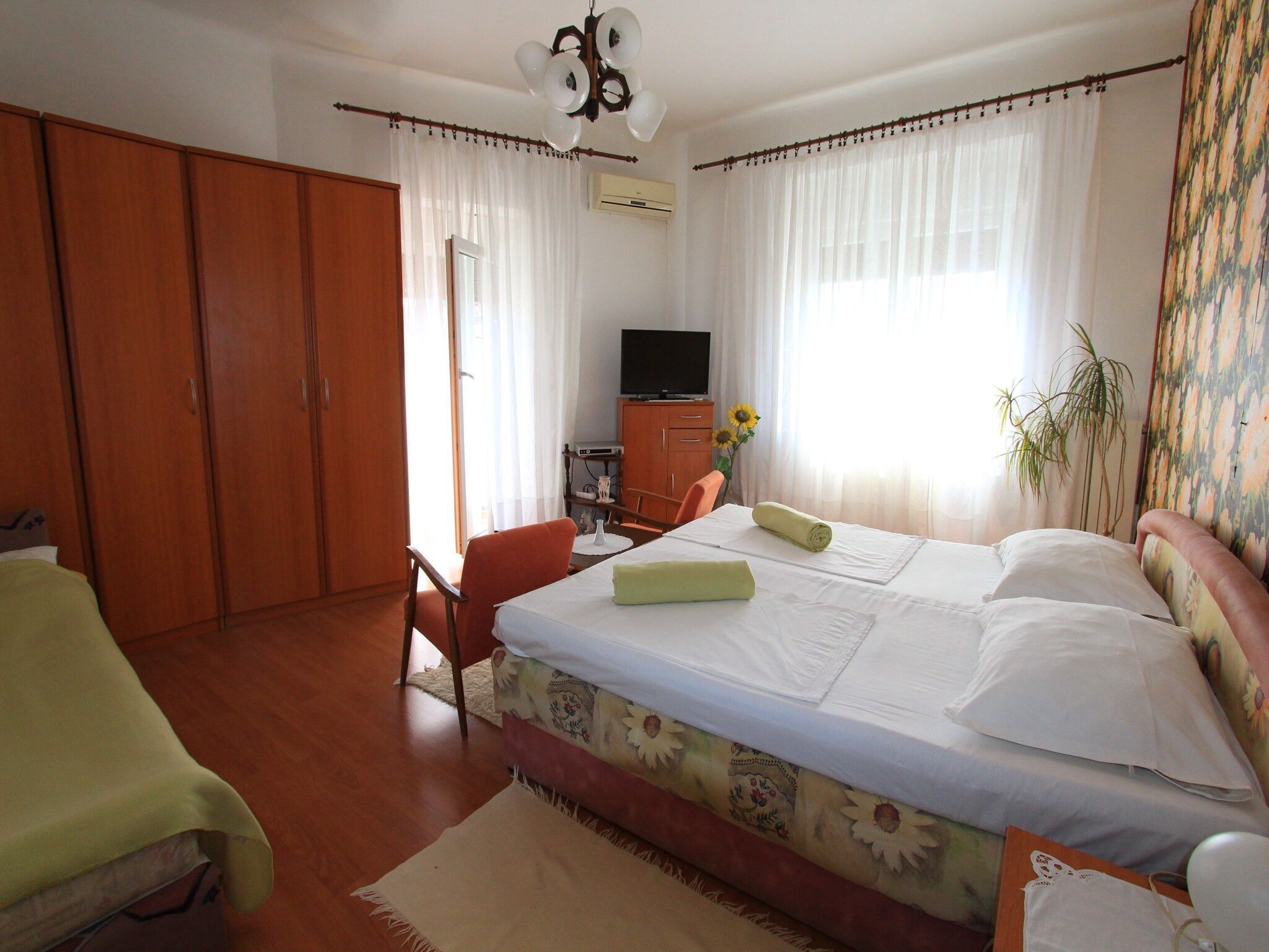 A hotel room with a bed, a desk, a chair, a television, and a wardrobe.