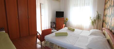 A hotel room with a bed, a desk, a chair, a television, and a wardrobe.