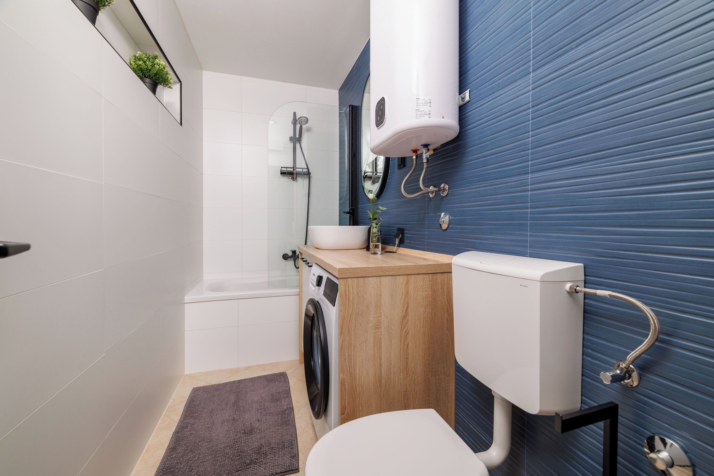 Une salle de bain moderne équipée d’un lave-linge, de toilettes, d’un lavabo et d’une douche.