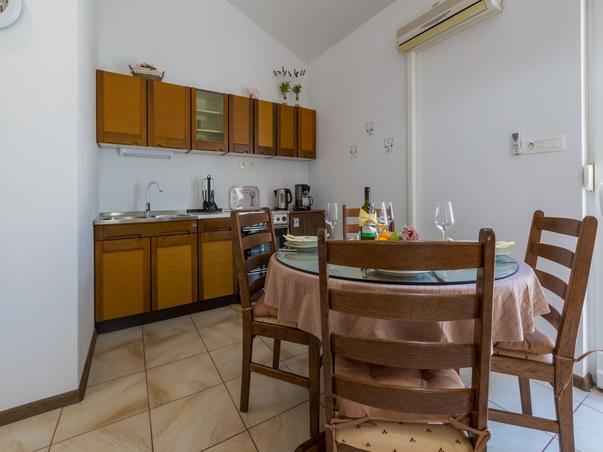 A compact kitchen with wooden cabinets and a dining area with a round table and chairs.