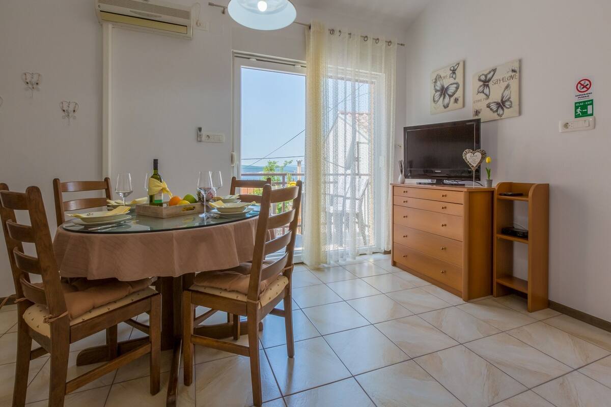 Un comedor con una mesa redonda, sillas y un televisor sobre un mueble de madera.
