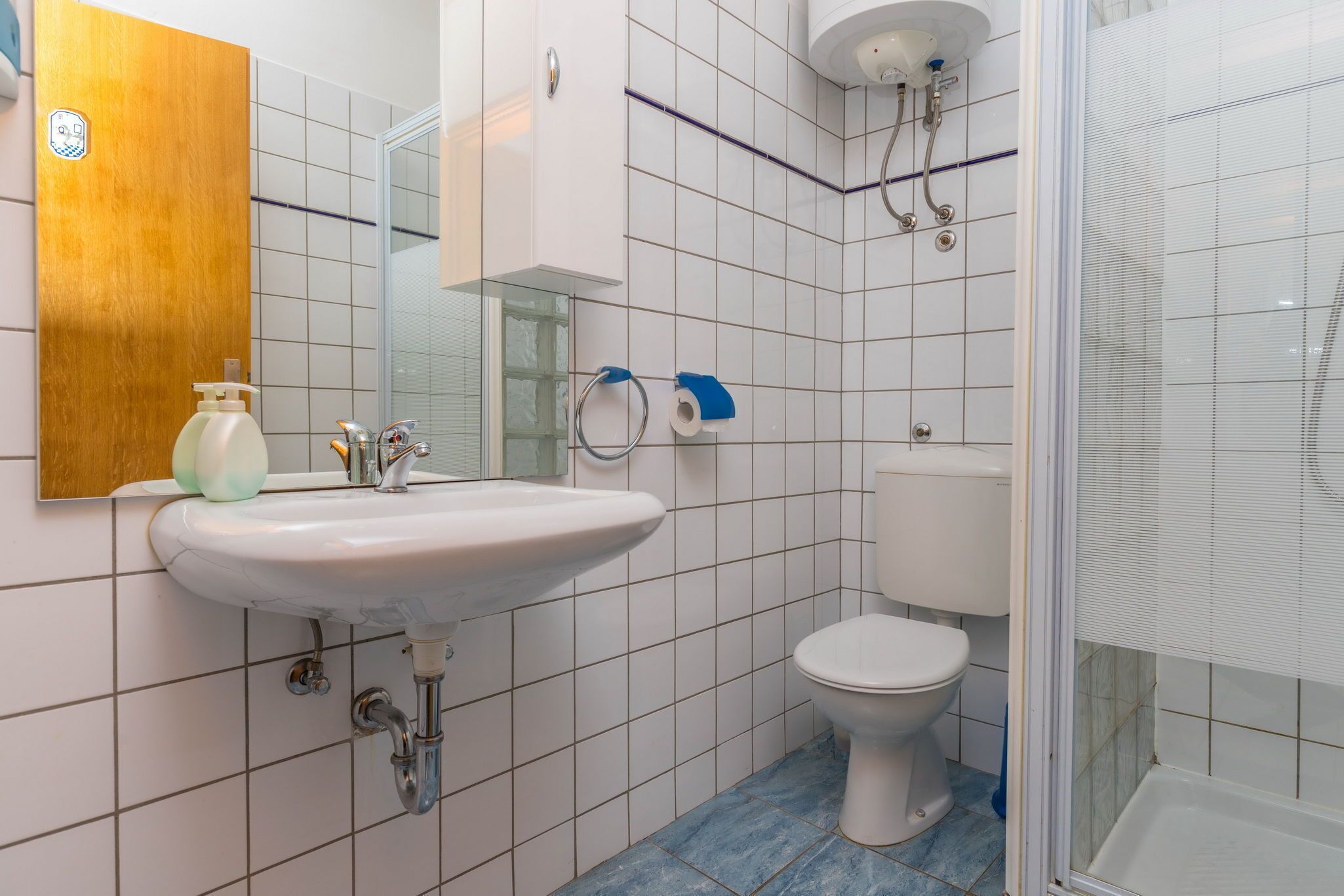 A bathroom with a white sink, toilet, and shower.