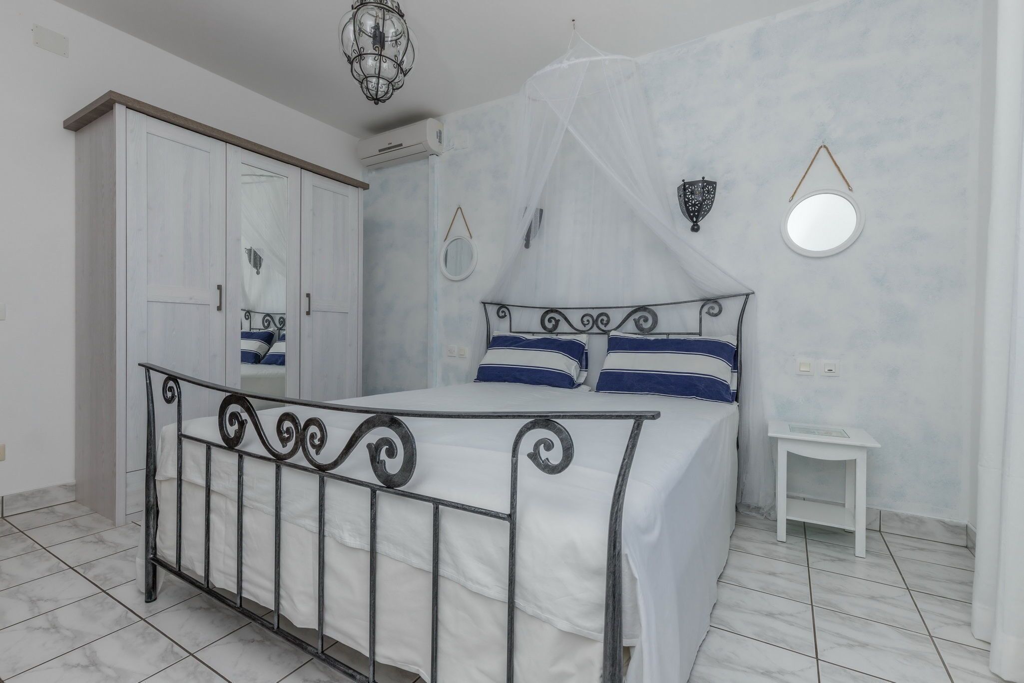 A bedroom with a bed, wardrobe, bedside table, and decorative wall elements.