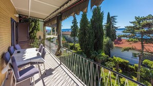 Un balcon avec une table et des chaises, offrant une vue panoramique sur des arbres et une étendue d’eau.