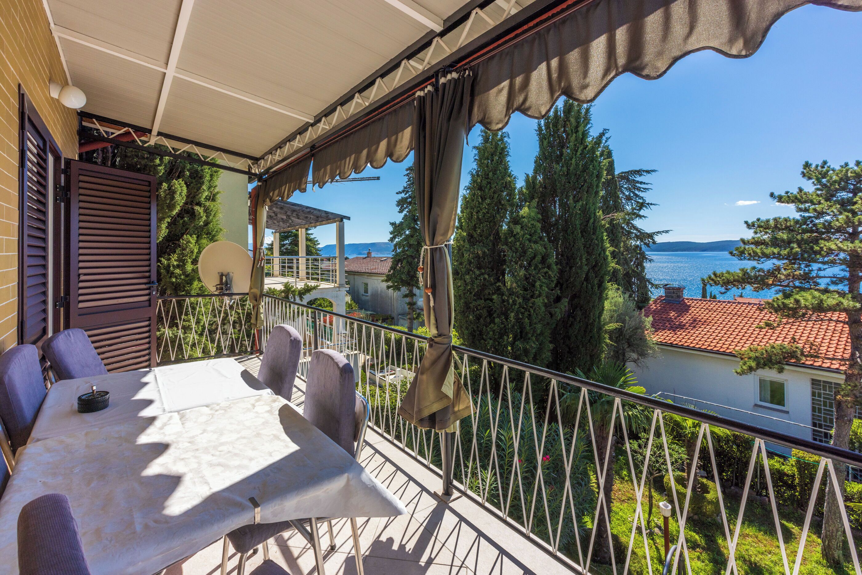Un balcon avec une table et des chaises, offrant une vue panoramique sur un lac et des bâtiments.