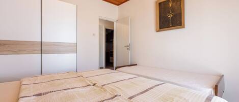 A bedroom with a large bed, a wardrobe, and a door leading to another room.