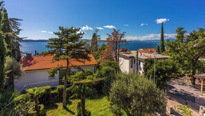 Une propriété située sur la côte, avec une maison à toit de tuiles rouges, un bâtiment blanc et une vue sur la mer.