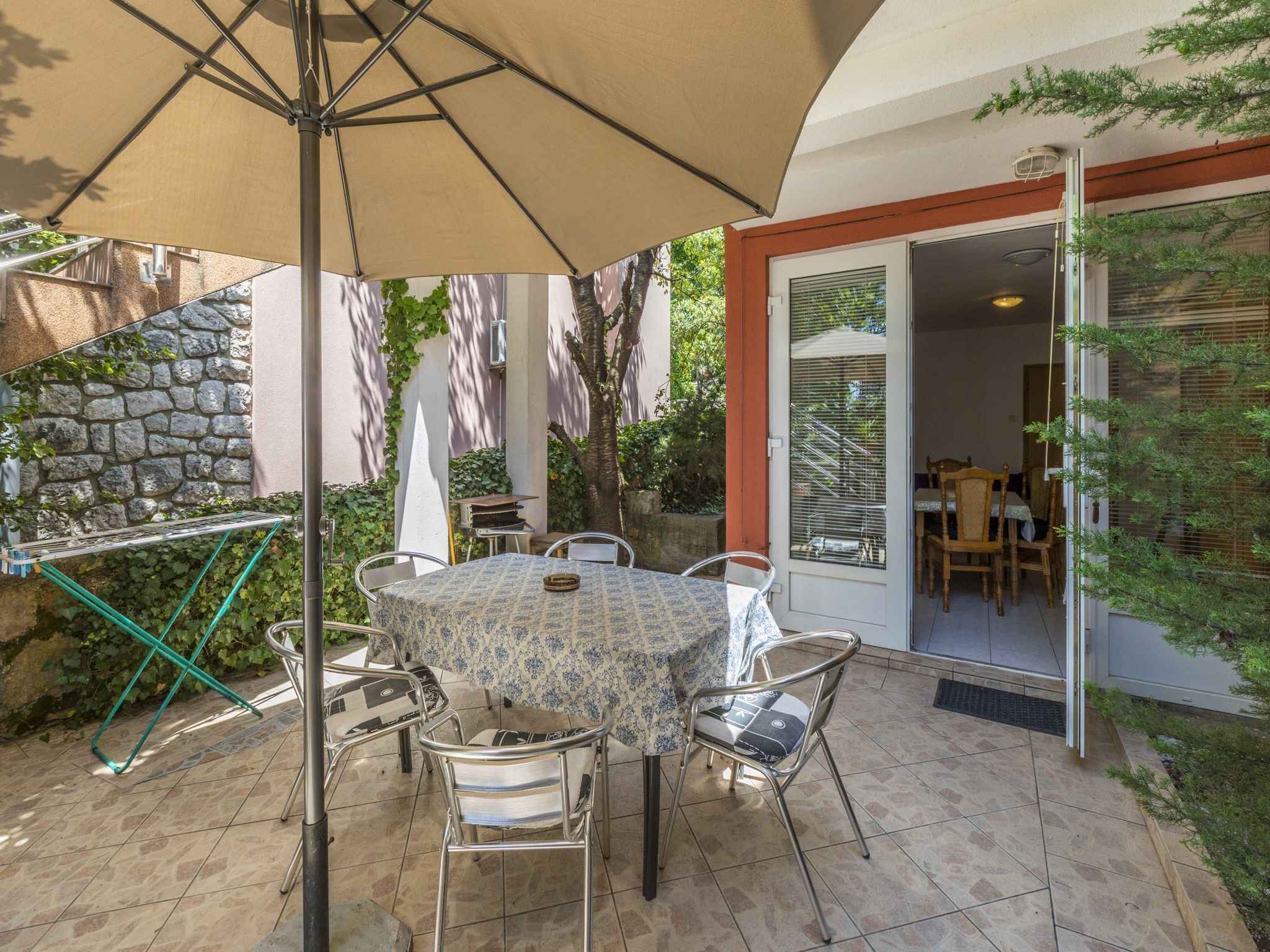 A patio with a table and chairs, a large umbrella, and a stone wall.