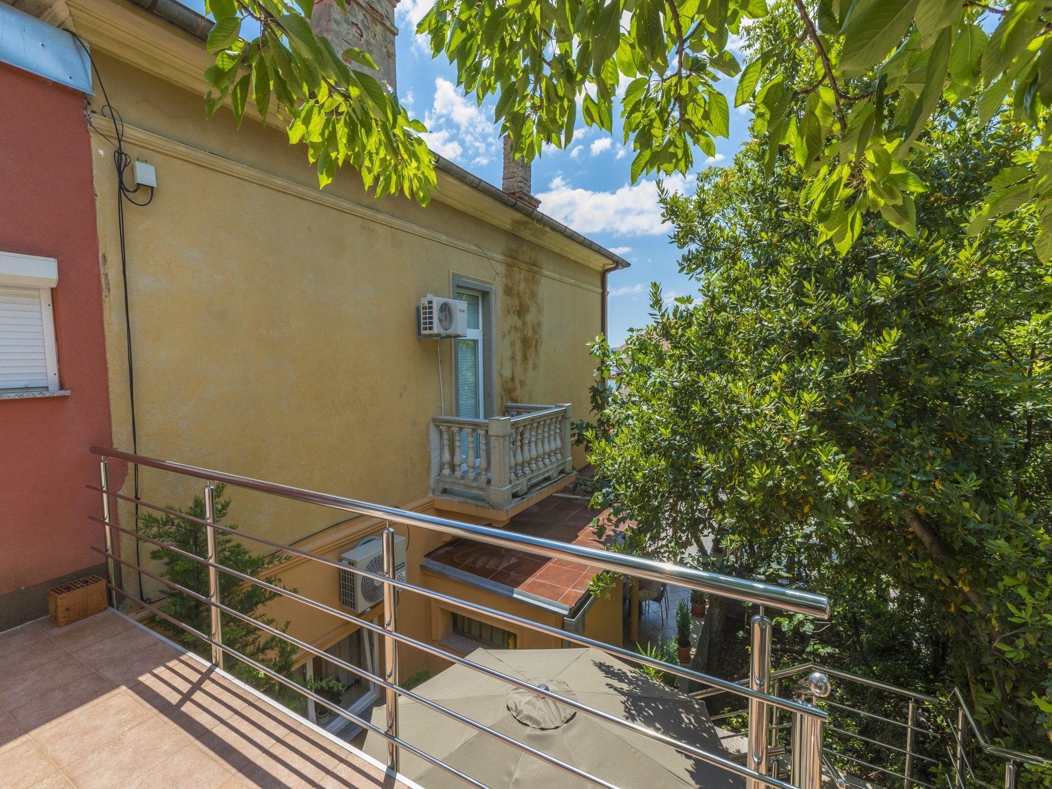 A residential building with a balcony, outdoor furniture, and a staircase.