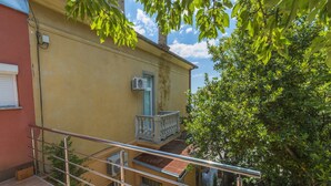 A residential building with a balcony, outdoor furniture, and a staircase. - Apartments Vilma (Crikvenica)