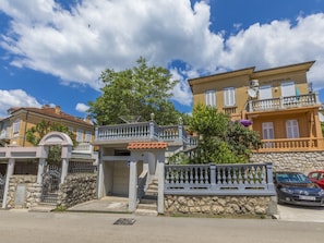 A villa with a stone wall, a gated entrance, and a balcony.