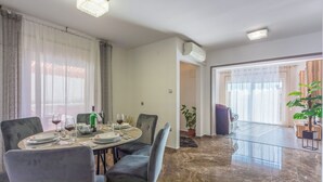 A dining area with a round table set for four, chairs, and a chandelier. - Apartment Paula (Jadranovo)