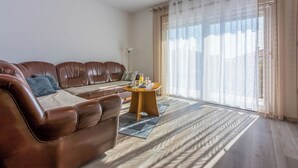 A modern living room with a brown leather sofa, a round wooden coffee table, and a patterned rug. - Apartment Paula (Jadranovo)
