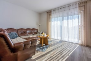 A living room with a brown leather sofa, a round wooden coffee table, and a patterned rug. - Apartment Paula (Crikvenica)