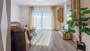A modern living room with a leather sofa, wooden TV stand, and a large plant. - Apartment Paula (Jadranovo)