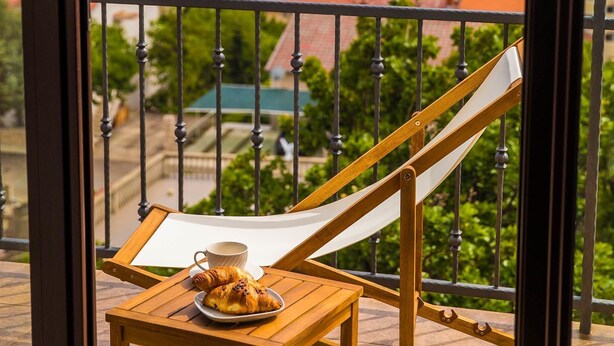 Ein Balkon mit Holztisch, einer Hängematte und einem Teller mit Essen und einer Tasse.