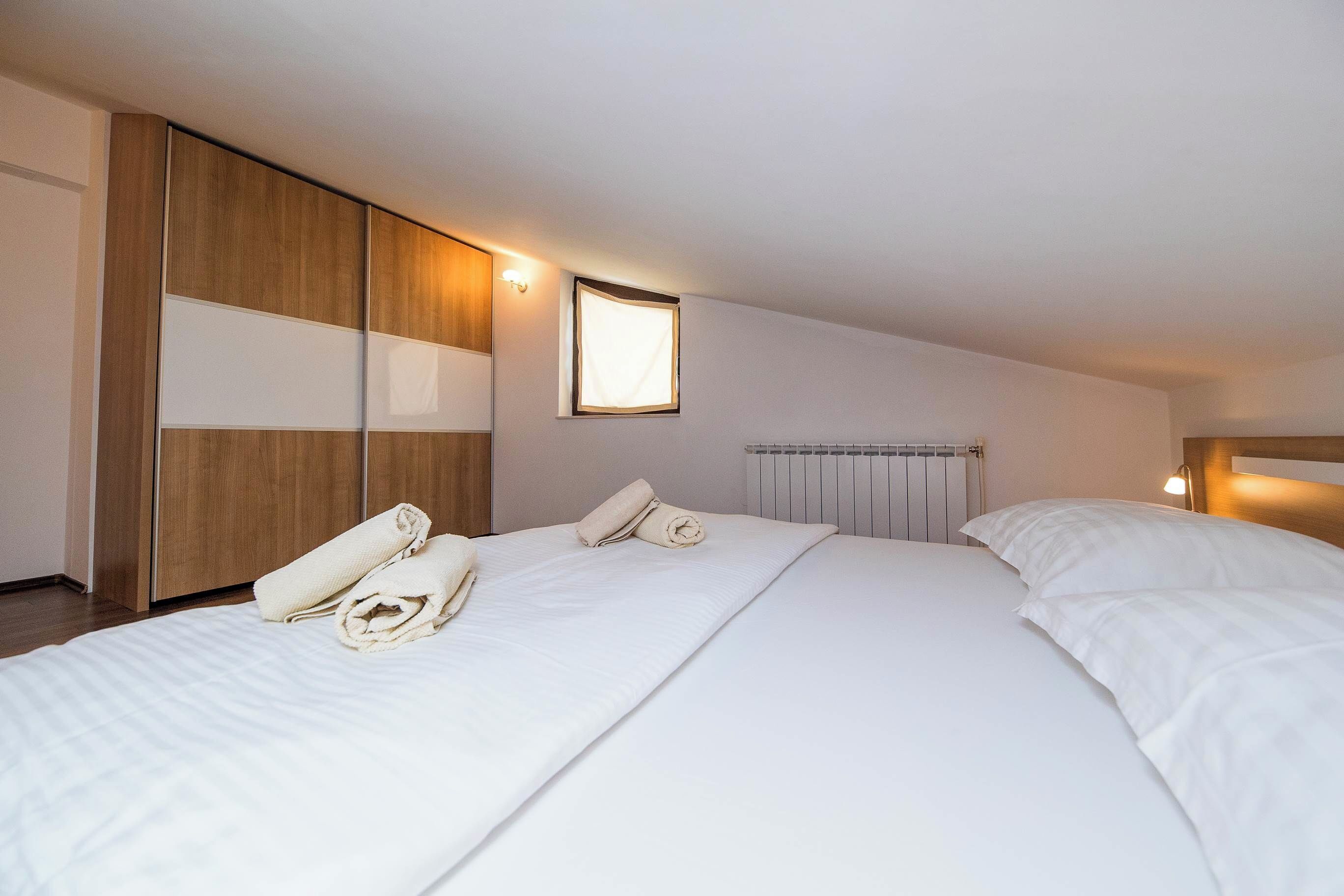 Une chambre d’hôtel avec un grand lit, une armoire en bois et une petite fenêtre.