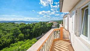 A balcony with a view of a lush green landscape and distant hills under a clear blue sky. - Apartment Blazic (Jadranovo)