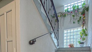 A staircase with a handrail, a vase with sunflowers, and a window with plants. - Apartment Blazic (Jadranovo)