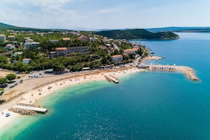 An aerial view of a coastal town with a beach, buildings, and a pier.