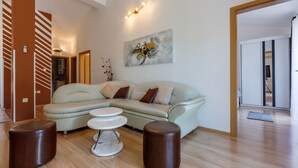 A modern living room with a sectional sofa, two round coffee tables, and a painting on the wall. - Apartments Barbara 2 (Jadranovo)